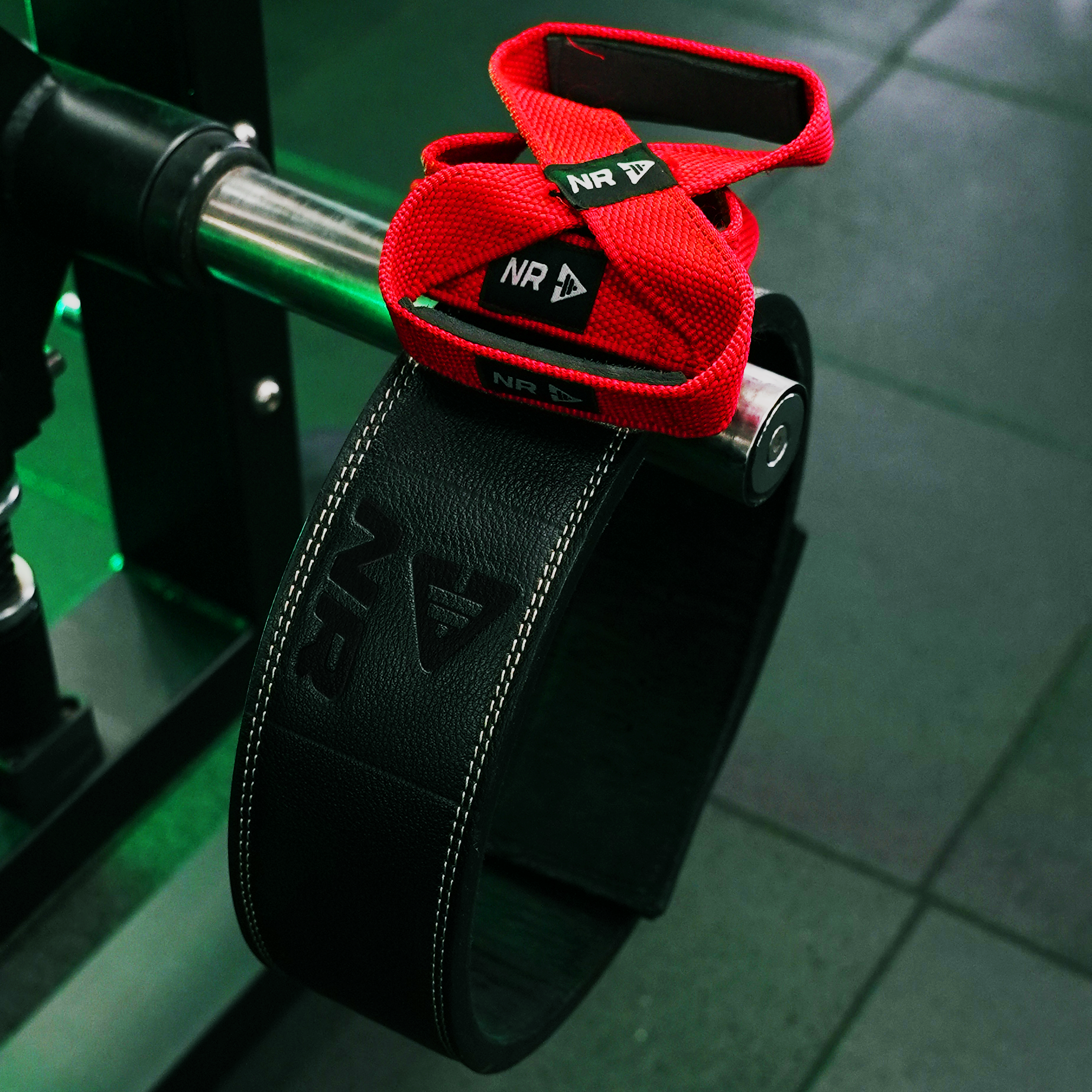 NXT REP Black weightlifting belt with red straps on a green weight bench